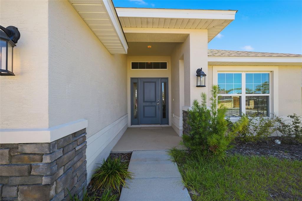 A front entryway with a blue door, stone accents, and a concrete walkway — 5524 OCEAN BREEZE DRIVE, SPRING HILL, FL