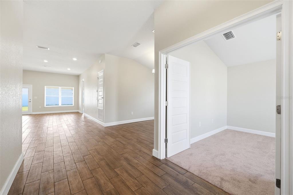A view from a hallway into a carpeted room and a tiled living area — 5524 OCEAN BREEZE DRIVE, SPRING HILL, FL