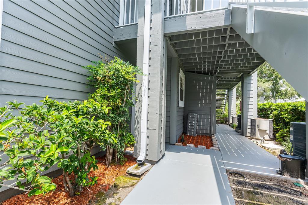 An exterior view shows a gray building with a covered walkway, stairs, and landscaping — 11942 SKYLAKE PLACE UNIT C, TAMPA, FL