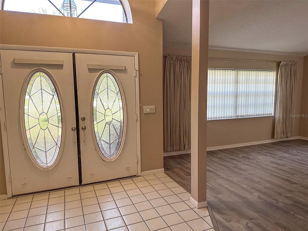 An entryway with tiled floors leads to a living area featuring wood-look flooring and windows — 8732 SKYMASTER DRIVE, NEW PORT RICHEY, FL