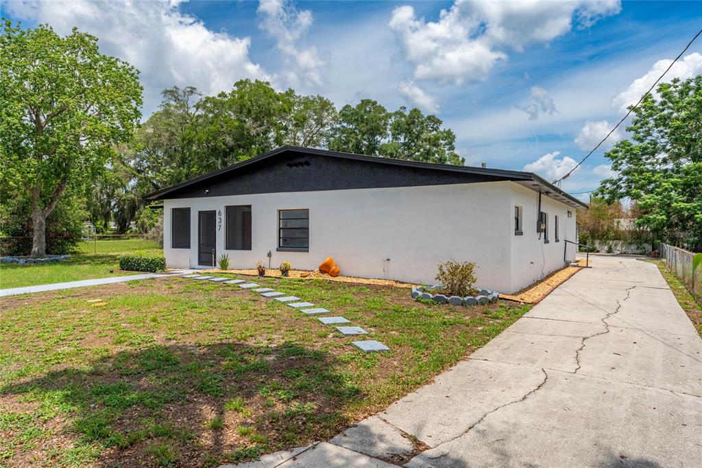 A white single-story house with a black roof and a long concrete driveway — 637 PASADENA AVENUE, LONGWOOD, FL