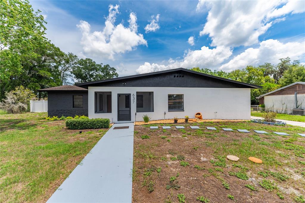 A single-story house with a white and black exterior features a walkway leading to the entrance — 637 PASADENA AVENUE, LONGWOOD, FL