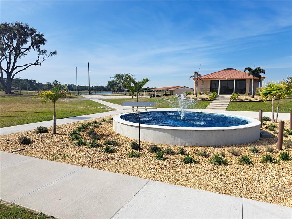 A circular fountain sits in a landscaped yard in front of a building with a porch — 604 CAMELLIA DRIVE, INDIAN LAKE ESTATES, FL