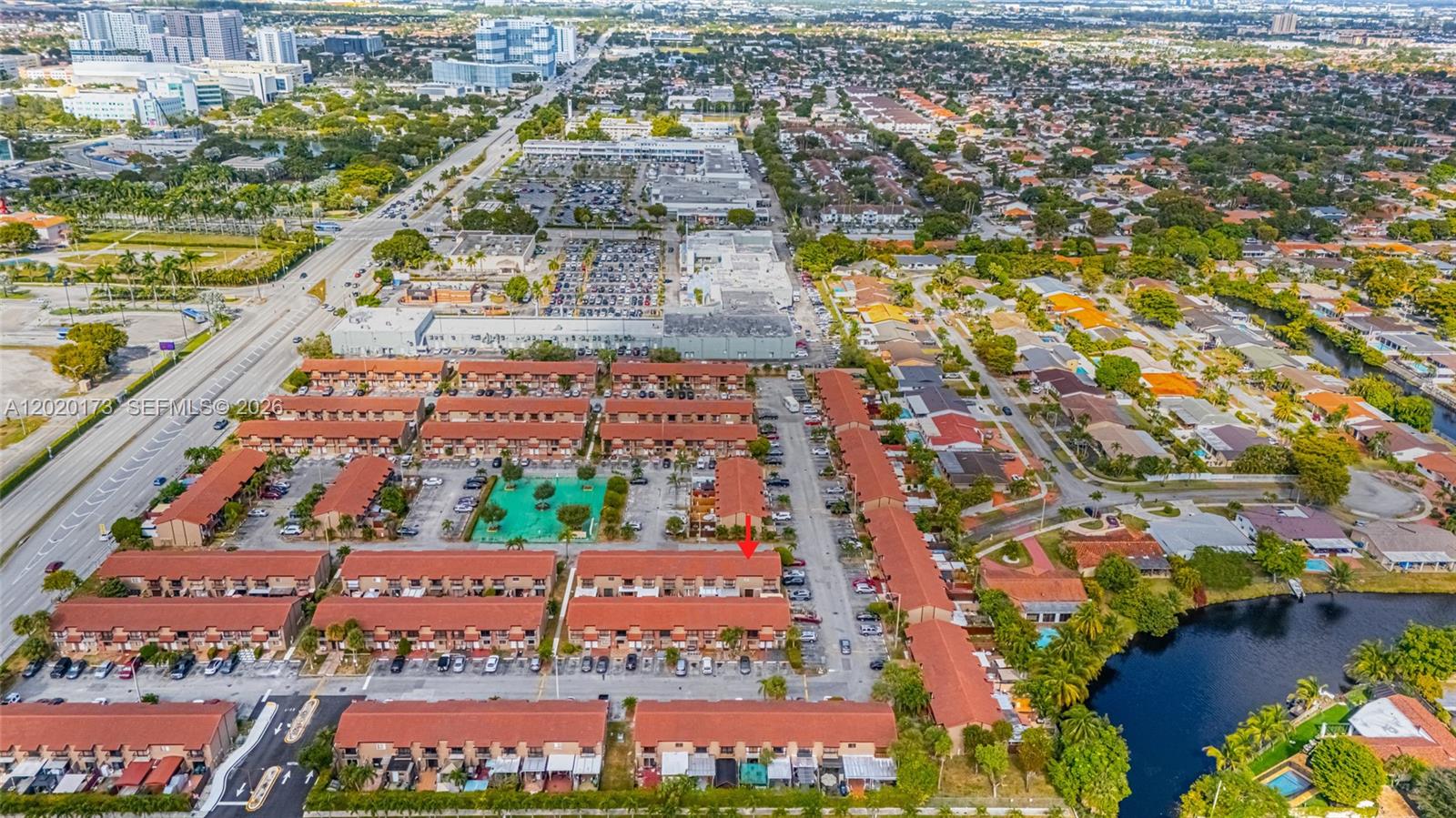 An aerial view shows a residential complex with red-roofed townhouses, parking lots, and a lake — 1911 SW 107th Ave # 1009, Miami FL 33165, MIAMI, FL
