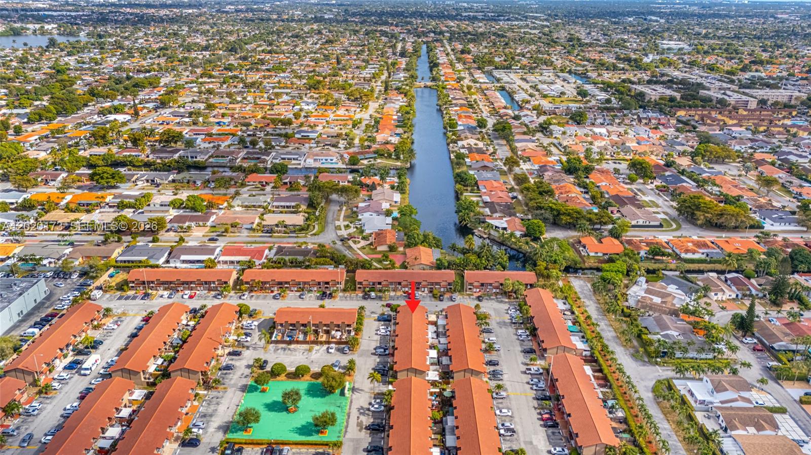 An aerial view shows a residential complex with red-tiled roofs and a central canal — 1911 SW 107th Ave # 1009, Miami FL 33165, MIAMI, FL