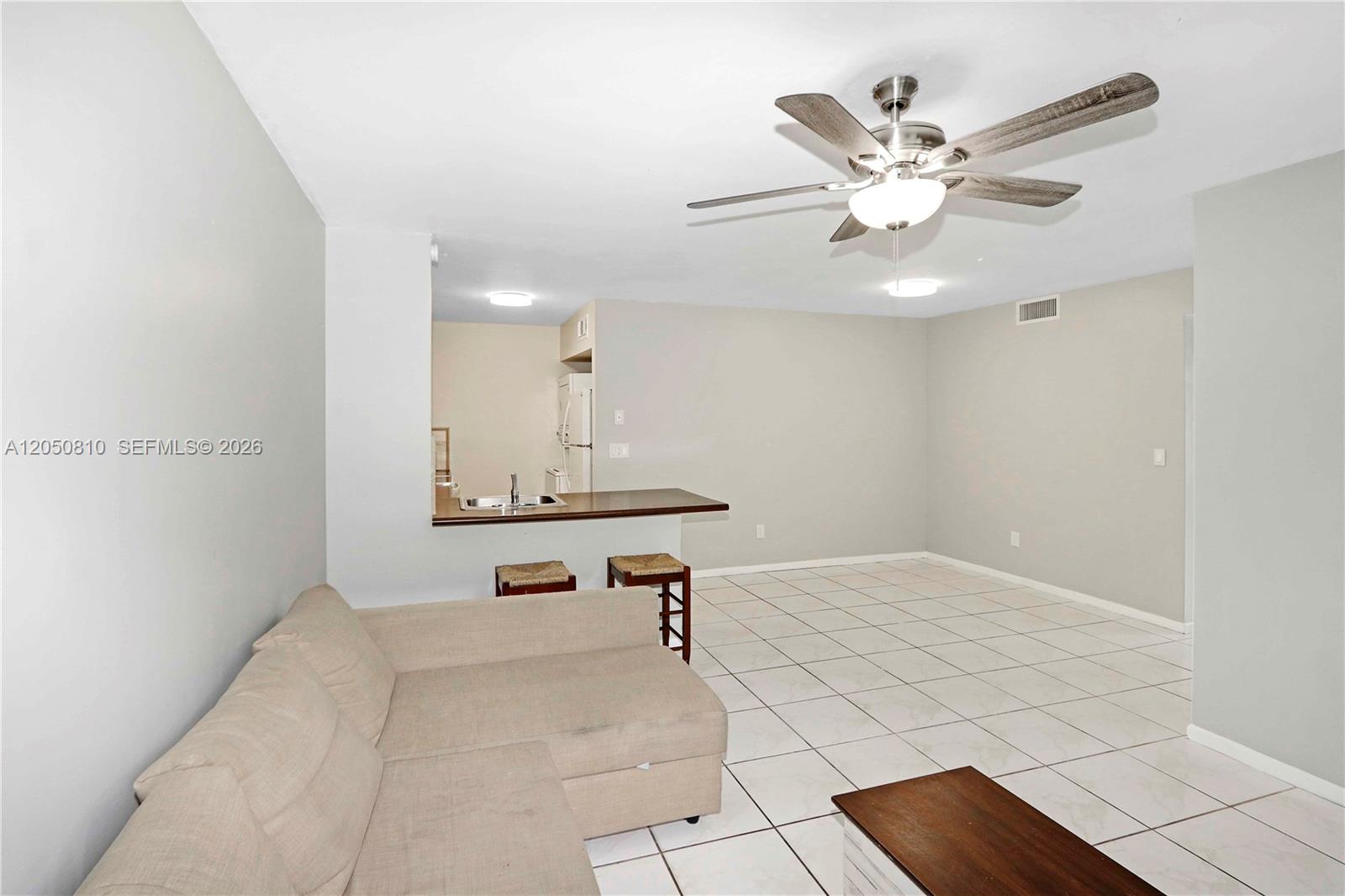 A living room with light-colored tile floors, a sectional sofa, and a kitchen breakfast bar — 2530 W 67th Pl # 29, Hialeah FL 33016, HIALEAH, FL