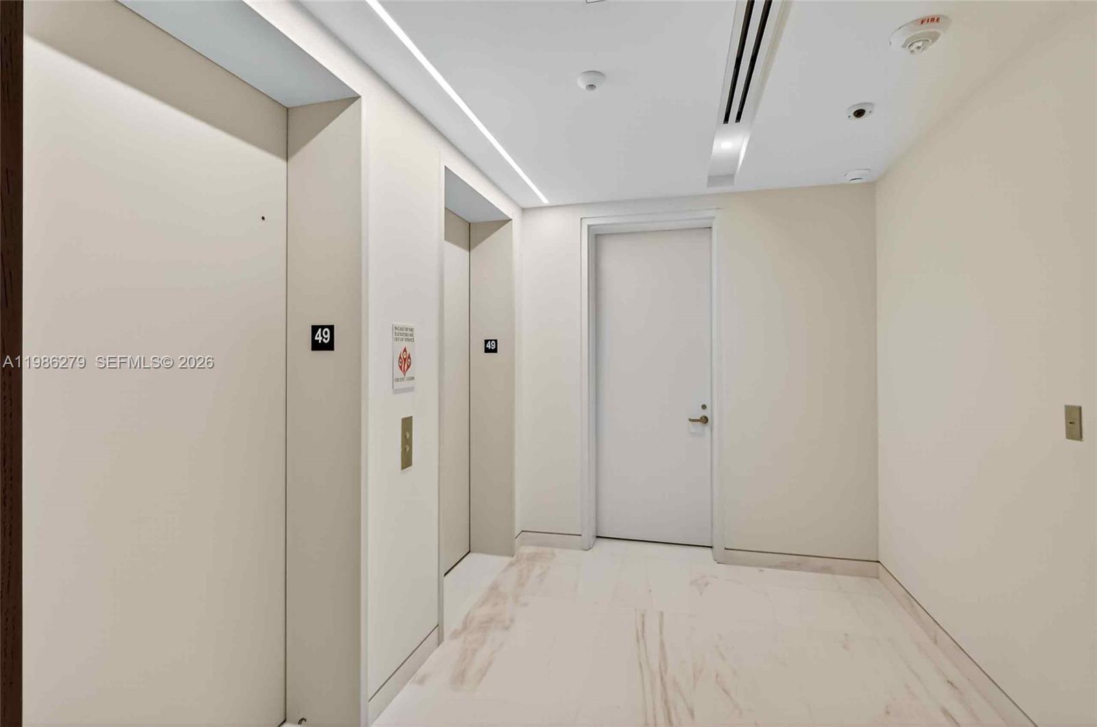 A bright hallway features white marble flooring, two elevator doors marked 49, and a door — 300 Biscayne Blvd Way # 4901E, Miami FL 33131, MIAMI, FL