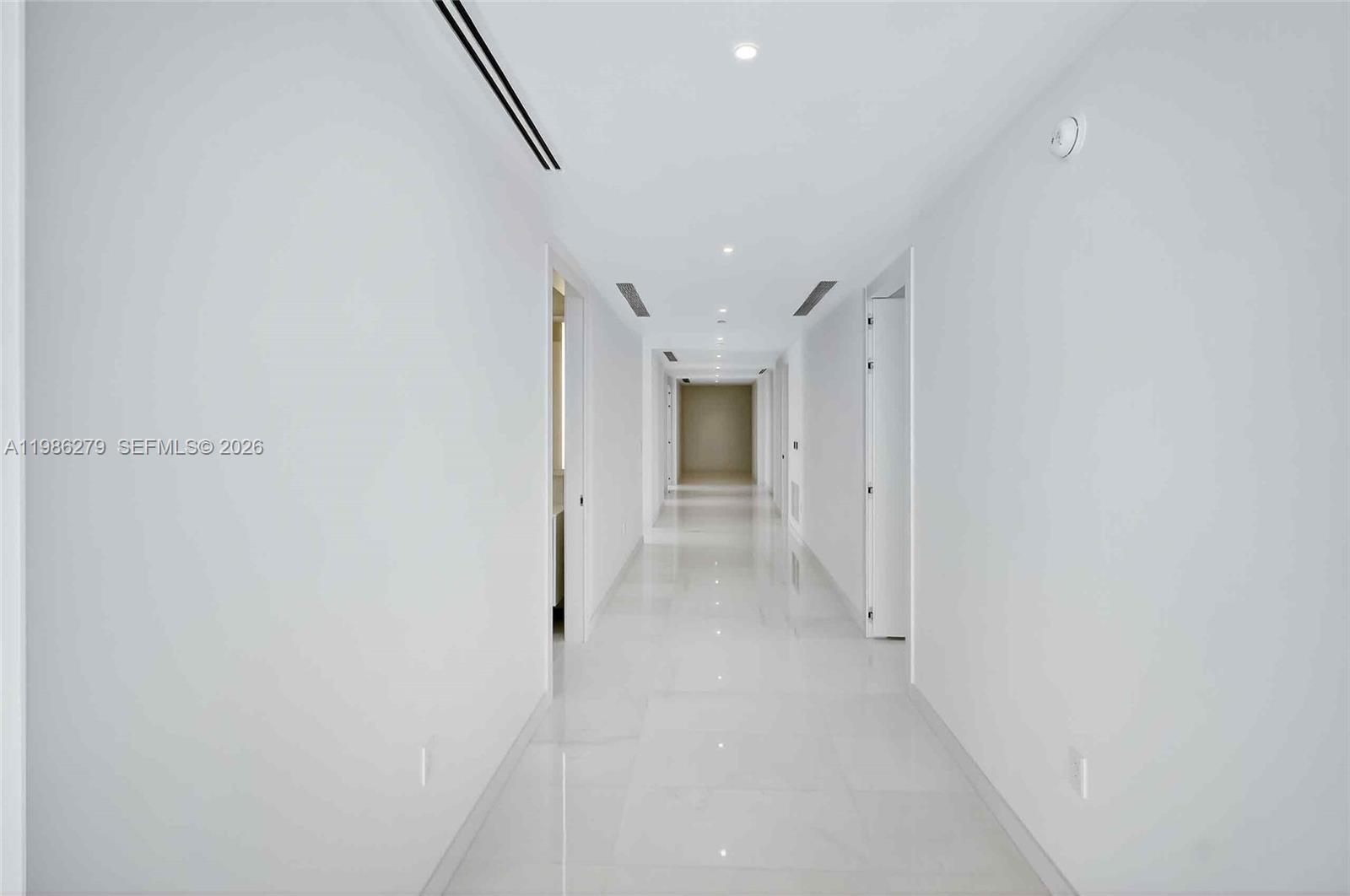 A long, white hallway features polished tile flooring and recessed ceiling lighting — 300 Biscayne Blvd Way # 4901E, Miami FL 33131, MIAMI, FL