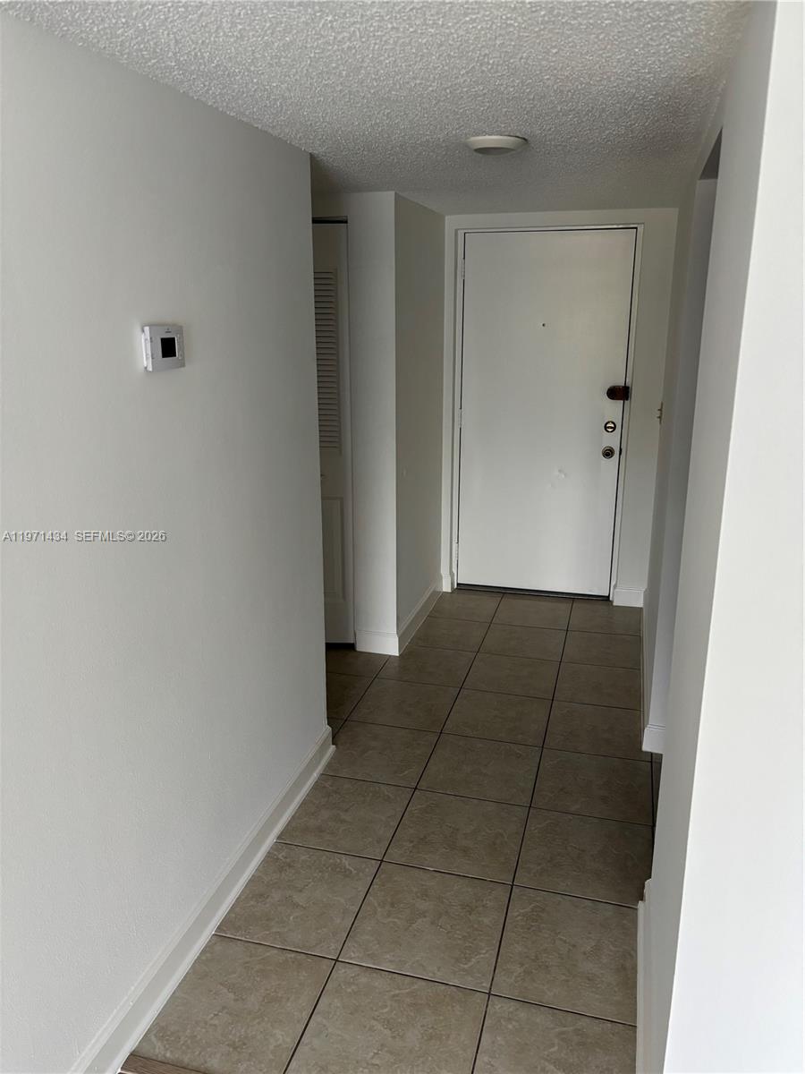 A tiled entryway features a white front door, a thermostat, and a louvered closet door — 7900 Camino Cir # 308, Miami FL 33143, MIAMI, FL
