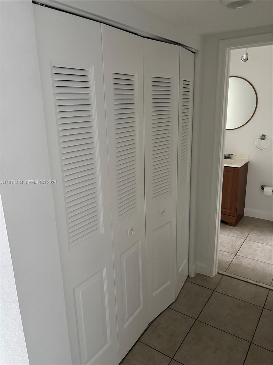White louvered closet doors stand next to an open doorway leading into a bathroom — 7900 Camino Cir # 308, Miami FL 33143, MIAMI, FL
