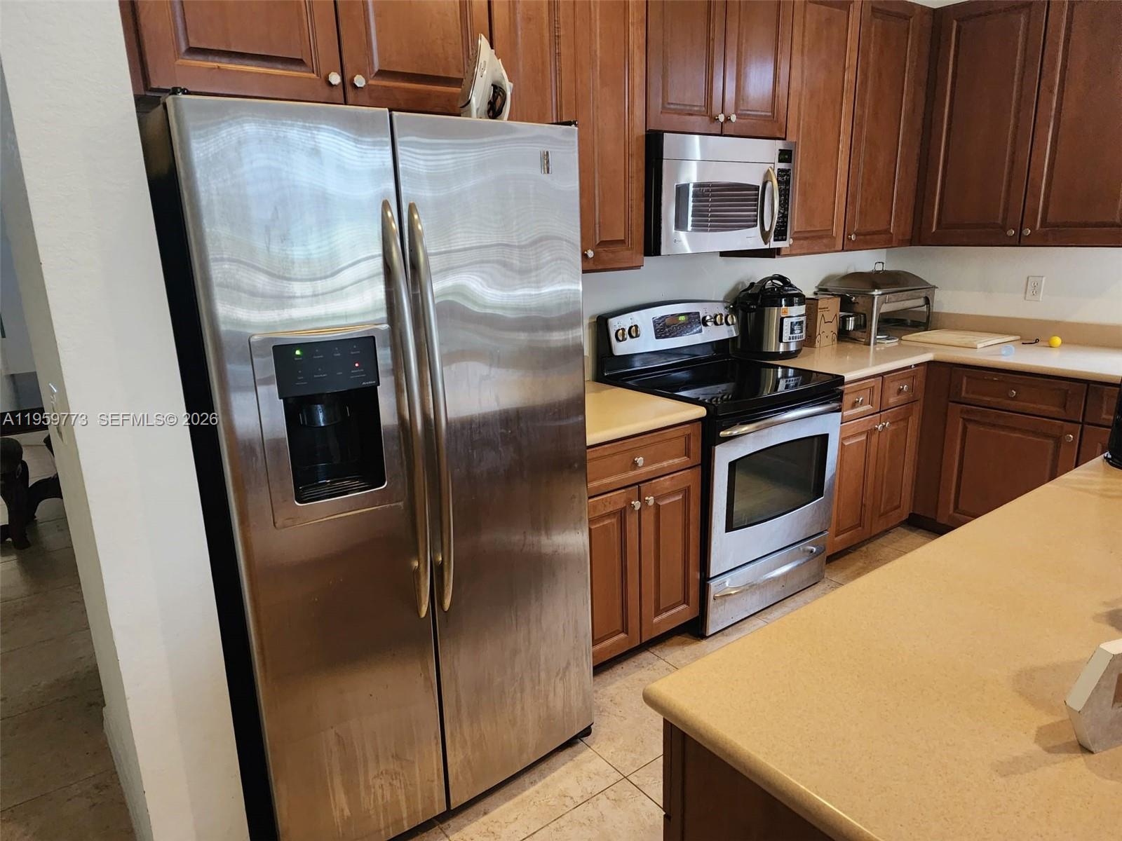 A kitchen features stainless steel appliances, wood cabinets, and beige countertops — 4155 Worlington Ter, Fort Pierce FL 34947, FORT PIERCE, FL