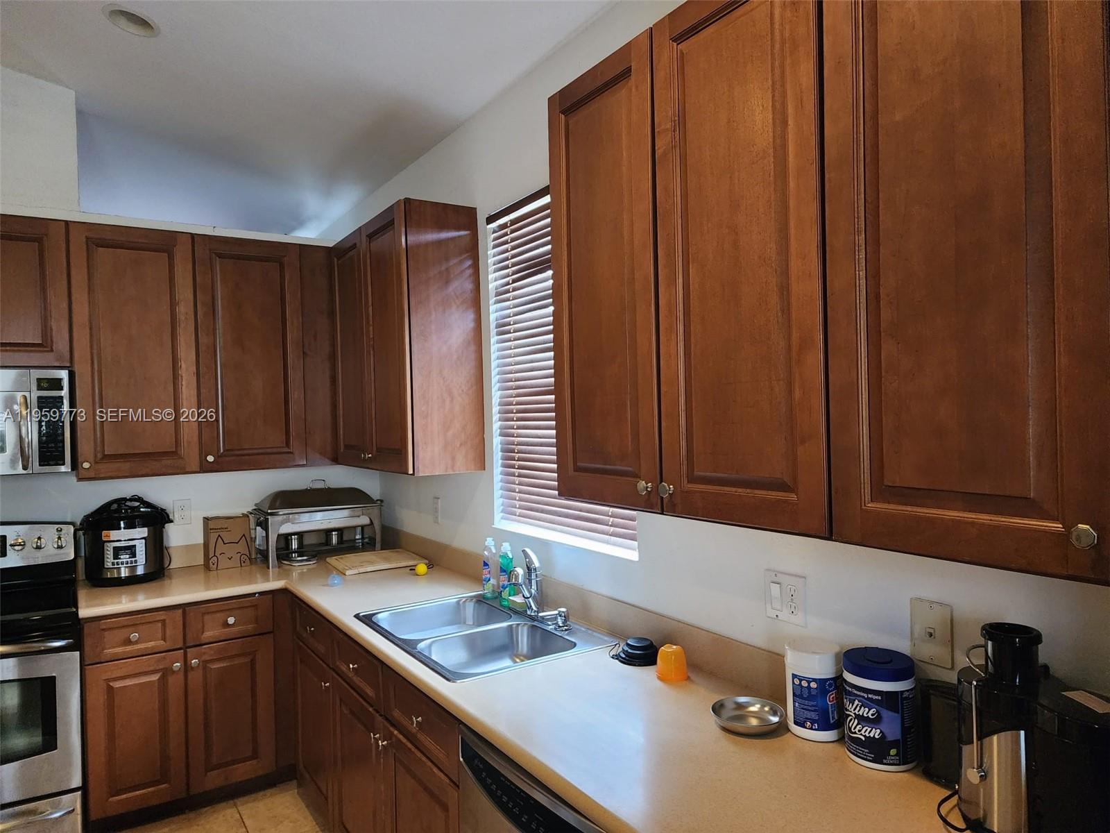 A kitchen features wood cabinets, a stainless steel sink, and light-colored countertops — 4155 Worlington Ter, Fort Pierce FL 34947, FORT PIERCE, FL