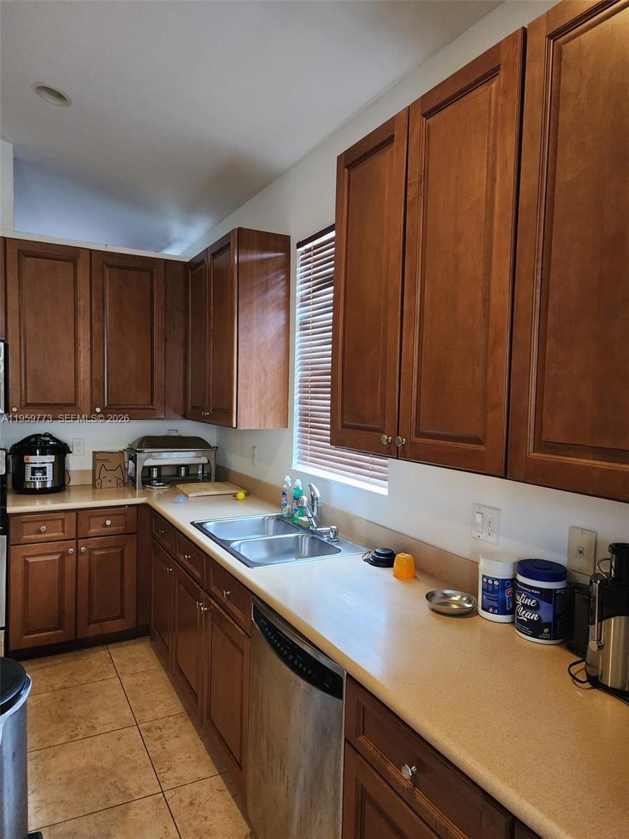 A kitchen features wood cabinets, a stainless steel dishwasher, and a double-basin sink — 4155 Worlington Ter, Fort Pierce FL 34947, FORT PIERCE, FL