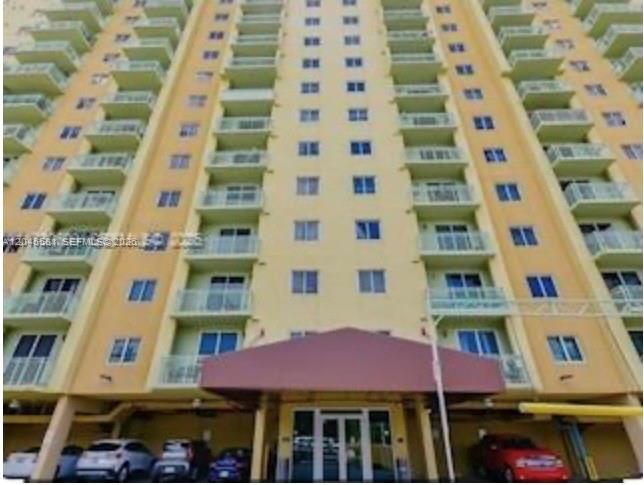 A low-angle view of a tall, yellow apartment building with multiple balconies and a canopy — 3500 Coral Way # 513, Miami FL 33145, MIAMI, FL
