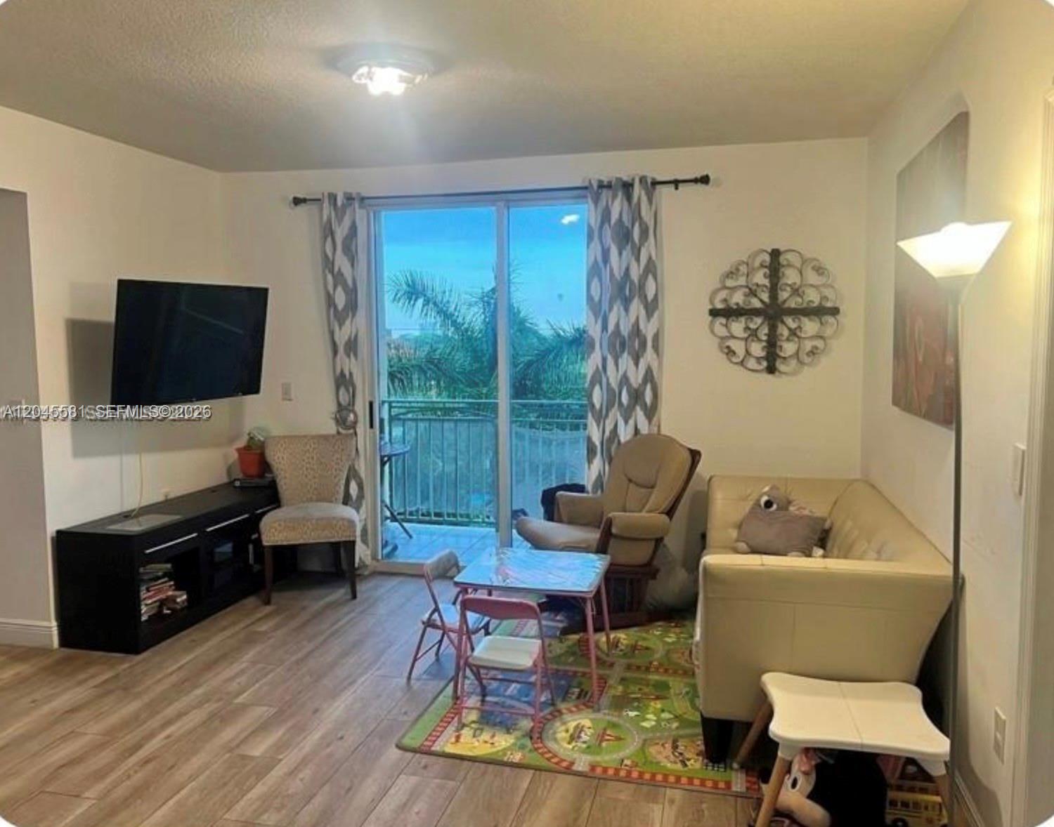 A living room features wood-look flooring, a sliding glass door, and a small children's table — 3500 Coral Way # 513, Miami FL 33145, MIAMI, FL