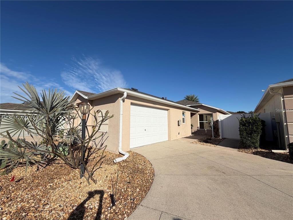 A beige single-story house features a white garage door and a concrete driveway — 1963 LADYFISH AVENUE, THE VILLAGES, FL