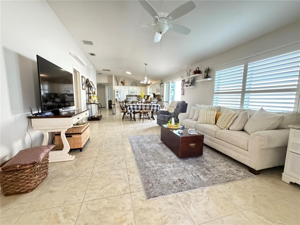 A living room with tile floors, a white sofa, and an open-concept kitchen beyond — 1963 LADYFISH AVENUE, THE VILLAGES, FL