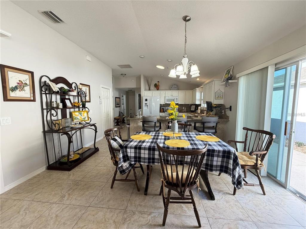A dining area with a plaid tablecloth, wooden chairs, and an open kitchen with bar seating — 1963 LADYFISH AVENUE, THE VILLAGES, FL