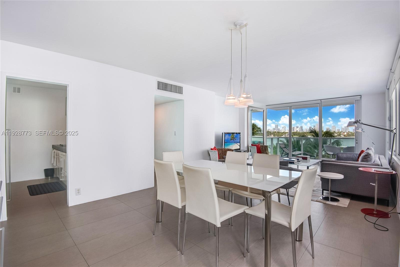 A dining area with a white table and chairs sits adjacent to a living room — 1000 West Ave # 311, Miami Beach FL 33139, MIAMI BEACH, FL