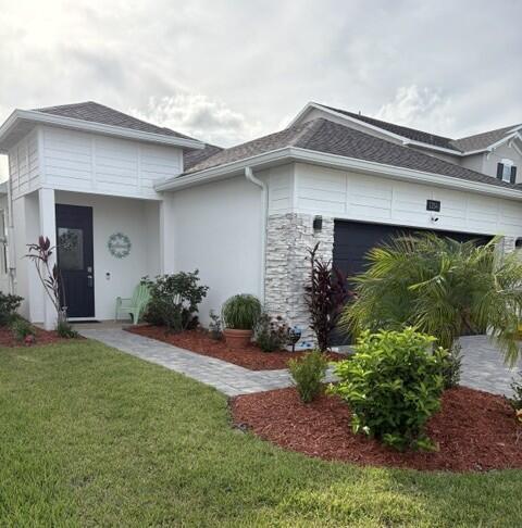 A white house with a stone facade, dark garage door, and a paved walkway — 1254 Canfield Circle SE, Palm Bay FL 32909, PALM BAY, FL