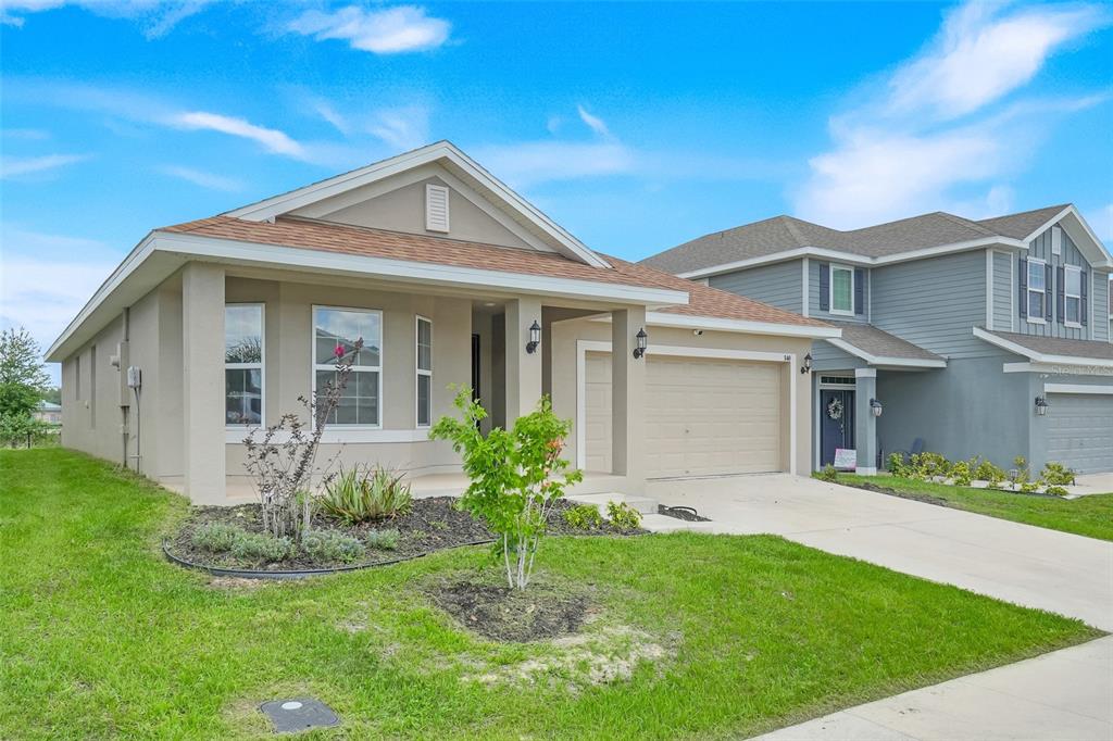 A single-story house with a tan exterior, a two-car garage, and a small front yard — 140 KRENSON BAY LOOP, WINTER HAVEN, FL
