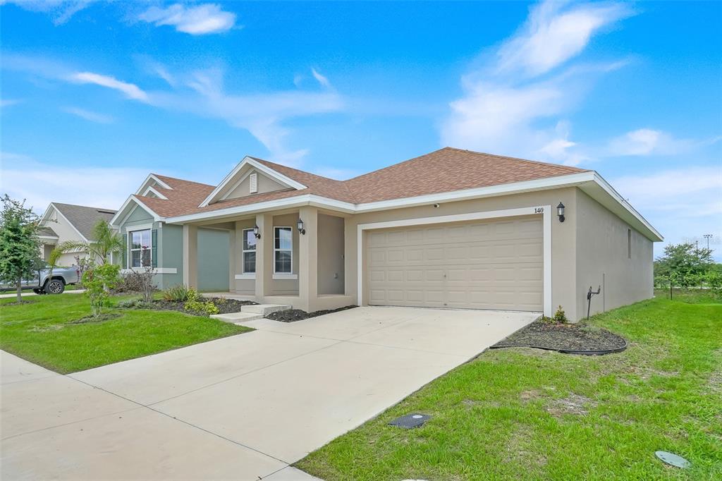 A tan single-story house with a two-car garage and a concrete driveway — 140 KRENSON BAY LOOP, WINTER HAVEN, FL