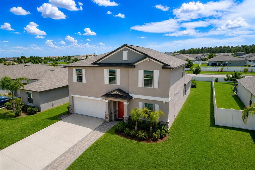An aerial view of a two-story suburban house with a beige exterior and red door — 13524 WILD GINGER STREET, RIVERVIEW, FL