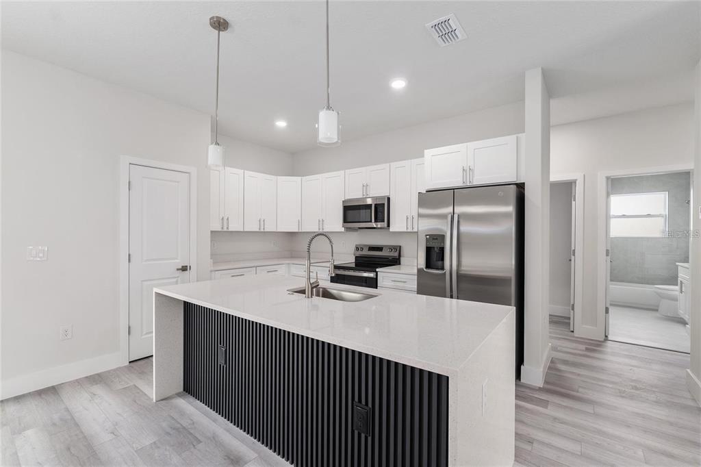 A modern kitchen features white cabinets, stainless steel appliances, and a black-slatted kitchen island — 13633 SW 82ND AVENUE, OCALA, FL