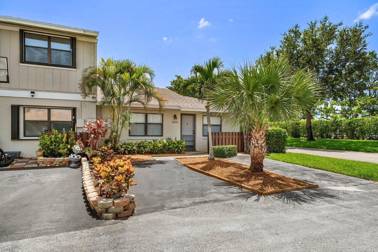 A single-story residential unit with a paved driveway, palm trees, and a small garden bed — 16422 Straw Way, Delray Beach FL 33484, DELRAY BEACH, FL