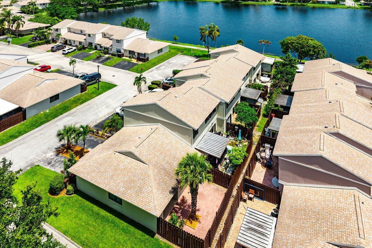 An aerial view shows several attached townhouses with tan roofs, fenced patios, and a lake — 16422 Straw Way, Delray Beach FL 33484, DELRAY BEACH, FL