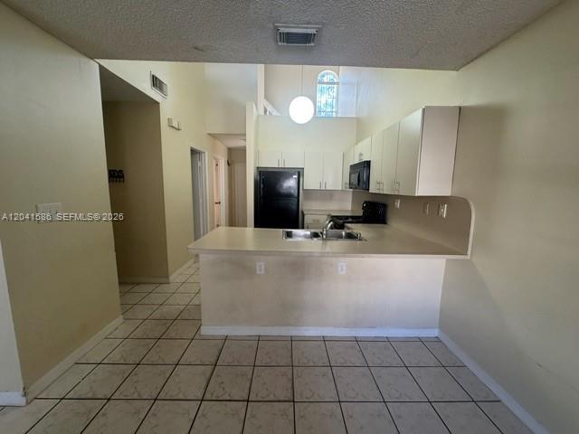 A kitchen features white cabinets, a black refrigerator, and a tiled floor — 3690 SW 153rd Pl, Miami FL 33185, MIAMI, FL