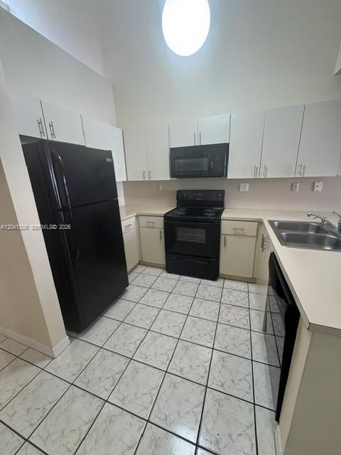A kitchen features white cabinets, black appliances, and light-colored tiled flooring — 3690 SW 153rd Pl, Miami FL 33185, MIAMI, FL