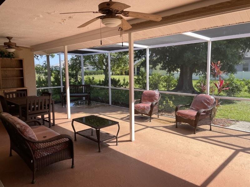 A screened-in patio features wicker furniture, a ceiling fan, and views of a grassy yard — 1472 NEAPOLITAN ROAD, PUNTA GORDA, FL