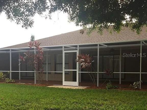 A screened-in patio with a concrete floor sits behind a grassy lawn — 1472 NEAPOLITAN ROAD, PUNTA GORDA, FL