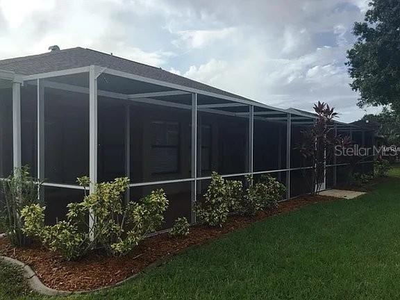A screened-in patio extends along the back of a house with a grassy yard — 1472 NEAPOLITAN ROAD, PUNTA GORDA, FL