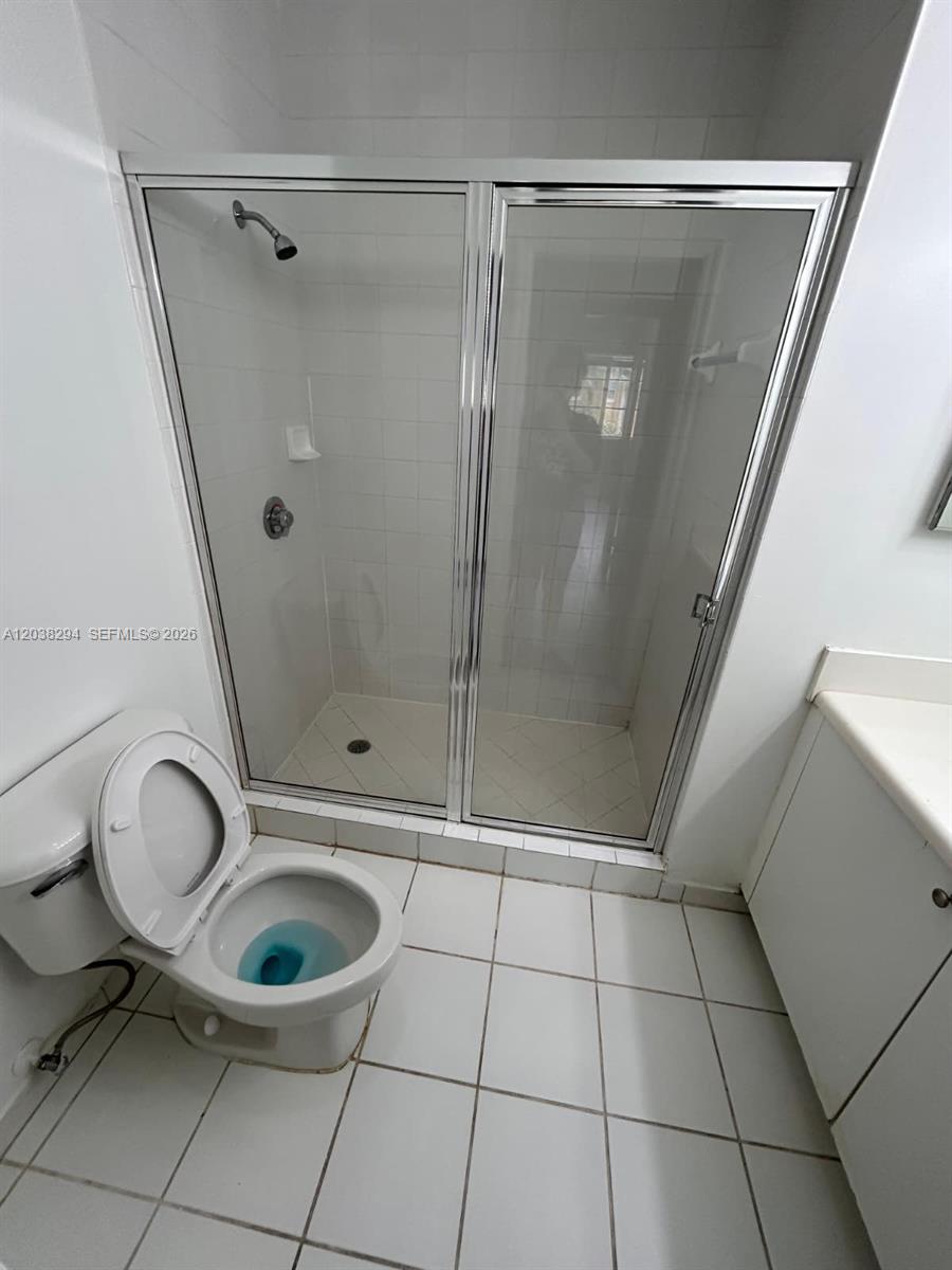 A bathroom features a white toilet, a glass-enclosed shower, and white tile flooring — 2440 E Preserve Way # 303, Miramar FL 33025, MIRAMAR, FL