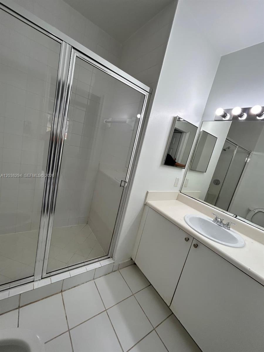 A bathroom features a glass-enclosed shower, a white vanity with a sink, and tiled flooring — 2440 E Preserve Way # 303, Miramar FL 33025, MIRAMAR, FL