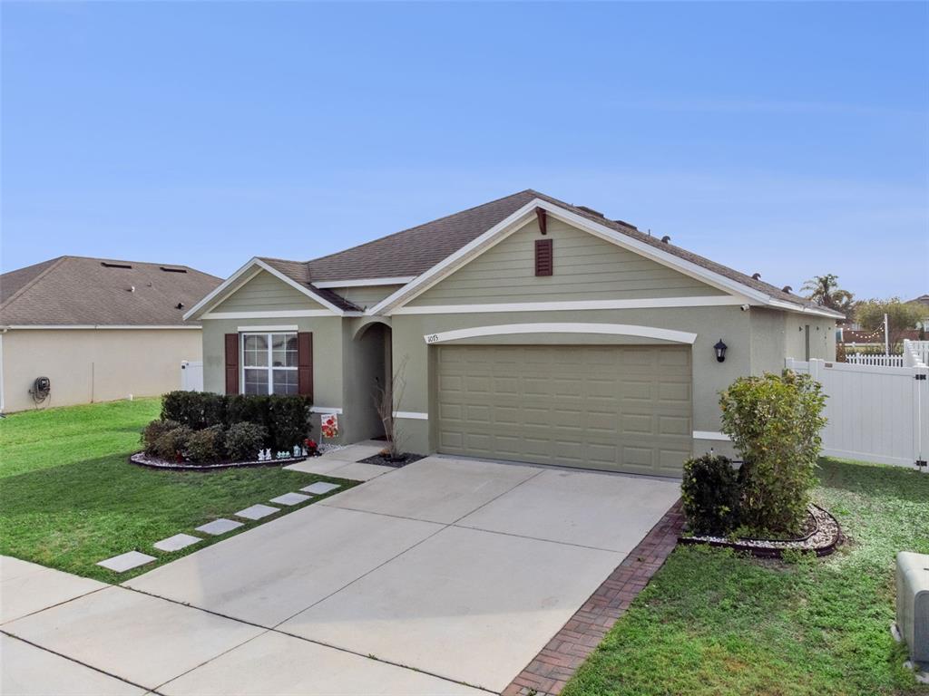 A single-story house with a green stucco exterior, a two-car garage, and a concrete driveway — 1073 PRESERVE DRIVE, DAVENPORT, FL