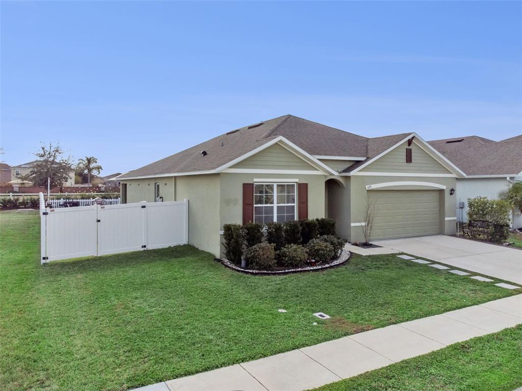 A single-story house with a green stucco exterior, a two-car garage, and a white fence — 1073 PRESERVE DRIVE, DAVENPORT, FL