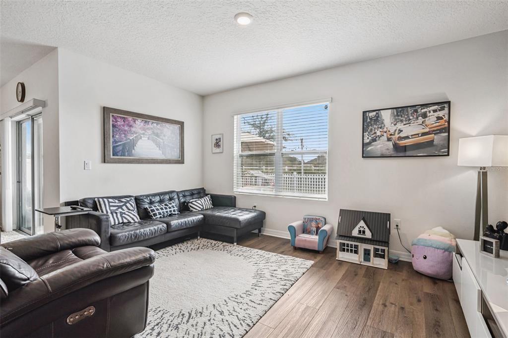 A living room features a dark sectional sofa, wood-look flooring, and a large window — 1073 PRESERVE DRIVE, DAVENPORT, FL
