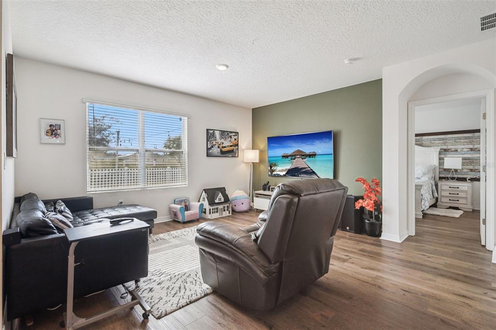 A living room features a black leather sofa, a recliner, and a wall-mounted television — 1073 PRESERVE DRIVE, DAVENPORT, FL