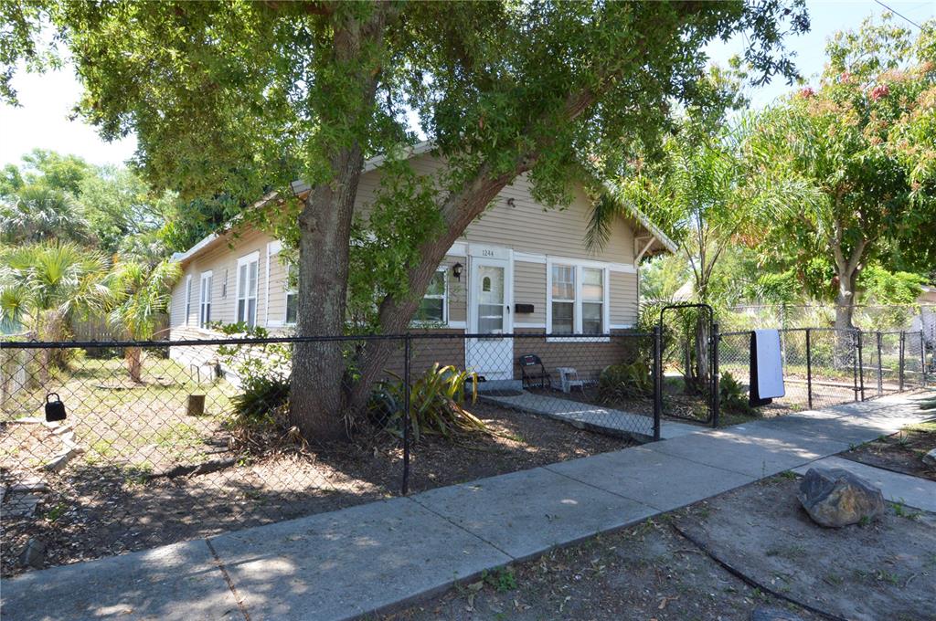 A tan, single-story house with a chain-link fence and a large tree in the yard — 1244 20TH AVENUE S, ST PETERSBURG, FL