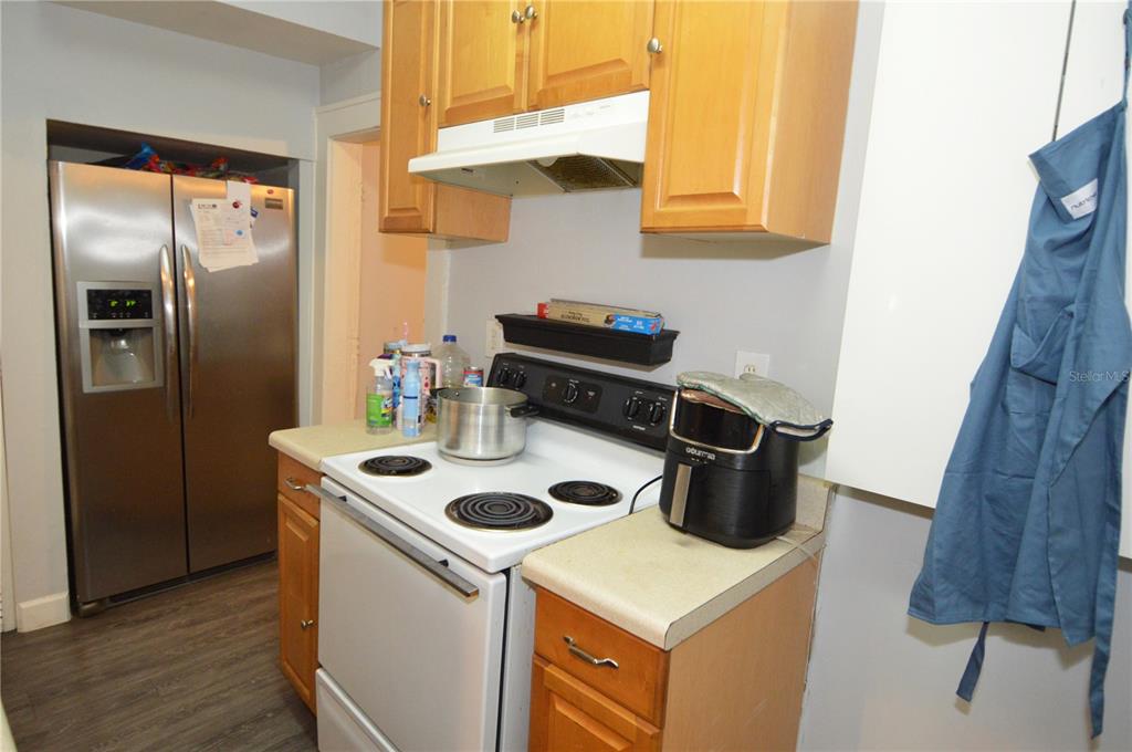 A kitchen features wood cabinets, a white electric stove, and a stainless steel refrigerator — 1244 20TH AVENUE S, ST PETERSBURG, FL