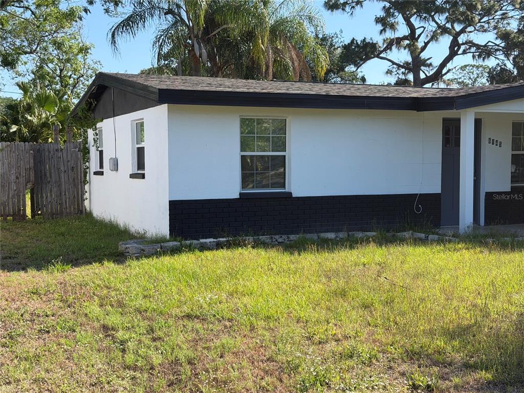 A single-story house with white stucco walls, a black brick base, and a dark roof — 6845 CAROB DRIVE, NEW PORT RICHEY, FL