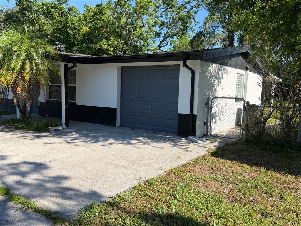 A single-story house with a white exterior, black trim, and a gray garage door — 6845 CAROB DRIVE, NEW PORT RICHEY, FL