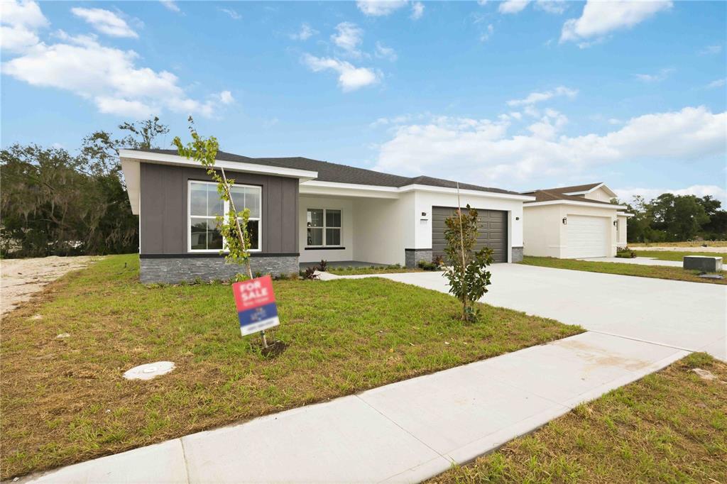 A modern single-story house with a gray and white exterior and a concrete driveway — 2112 RIVER HAWK LOOP, WINTER HAVEN, FL