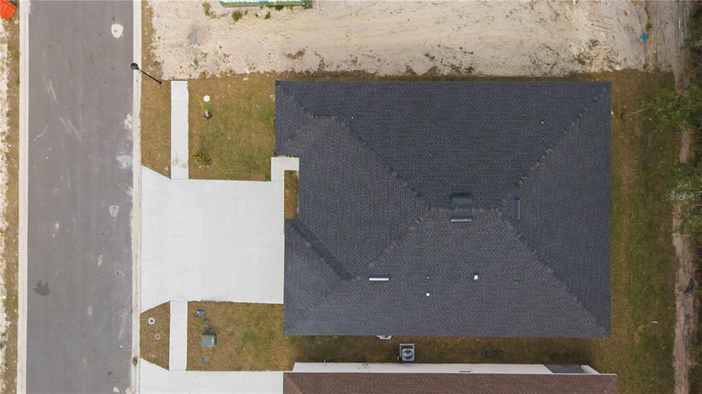 An aerial view shows the dark shingled roof of a house and its concrete driveway — 2112 RIVER HAWK LOOP, WINTER HAVEN, FL