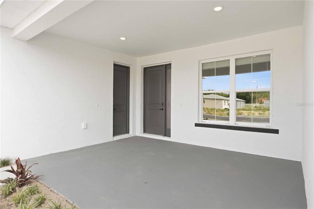 A covered concrete porch features two dark gray doors and a large window — 2112 RIVER HAWK LOOP, WINTER HAVEN, FL