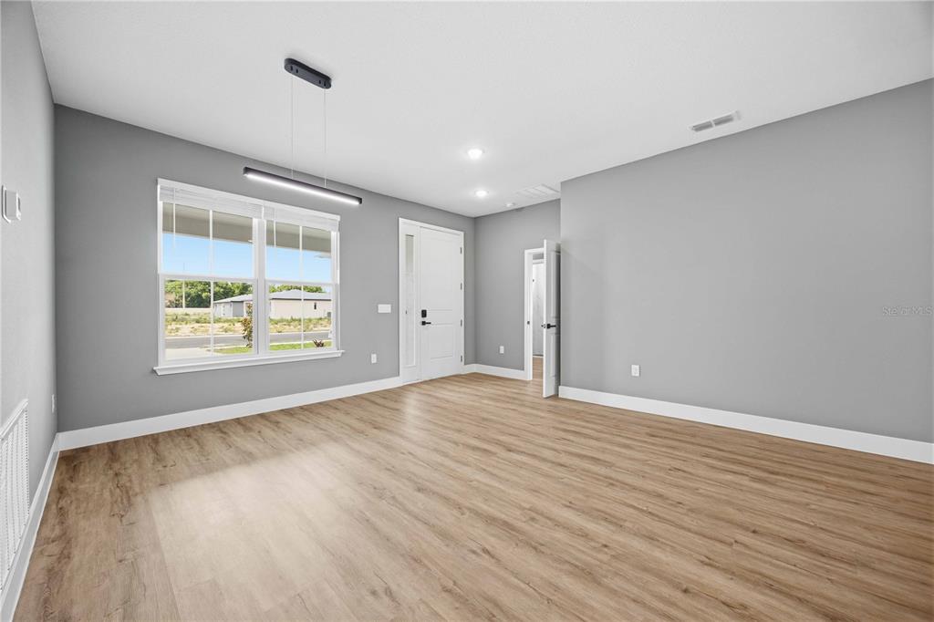 An empty room with gray walls, light wood-look flooring, a window, and a white door — 2112 RIVER HAWK LOOP, WINTER HAVEN, FL