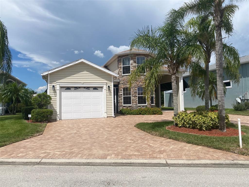 A two-story house with a stone facade, beige siding, and a paved driveway — 529 MEANDERING WAY, POLK CITY, FL